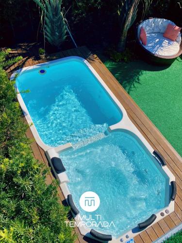 a pool in a yard with a wooden deck and a swimming pool at Rosa Internacional - Surfland in Praia do Rosa
