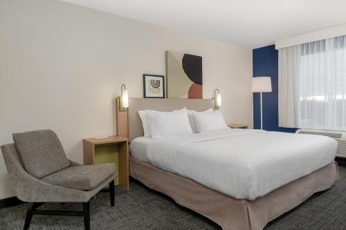 a hotel room with a bed and a chair at Spark by Hilton Murfreesboro in Murfreesboro