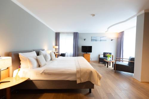 a bedroom with a large bed and a living room at Garner Hotel Friedrichshafen by IHG in Friedrichshafen