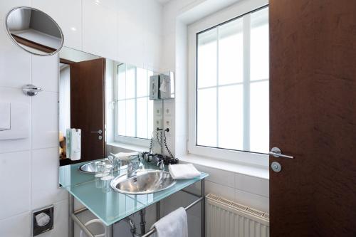 a bathroom with two sinks and a window at Garner Hotel Friedrichshafen by IHG in Friedrichshafen