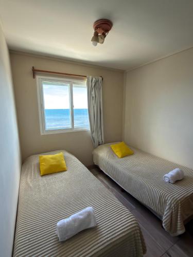 two beds in a room with a window at Departamento Torre IV in Comodoro Rivadavia