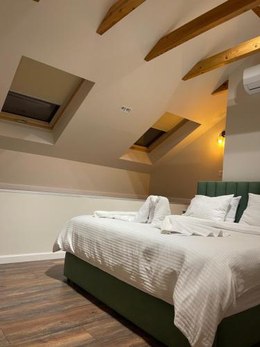 a bedroom with a bed with white sheets and wooden floors at Liams Cozy Villa in Korçë