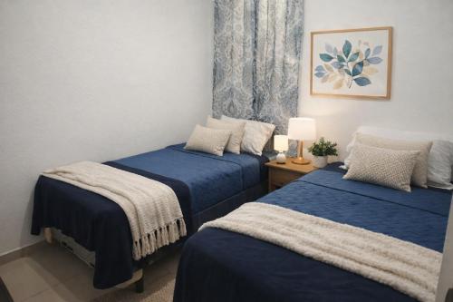 two beds in a room with blue sheets at Casa Socorrito in Ahuachapán