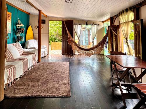 a living room with a couch and a hammock at Hostel Antônio Pescador - Centro da Guarda do Embaú in Guarda do Embaú