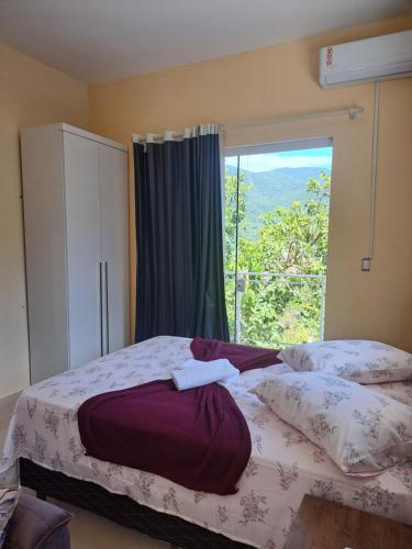 a bedroom with two beds and a large window at Sobradinho Morro dos Ventos in Palhoça
