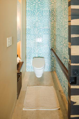 a bathroom with a toilet in a room with blue wallpaper at La Casa de la Playa by Xcaret- All Inclusive Adults Only in Playa del Carmen