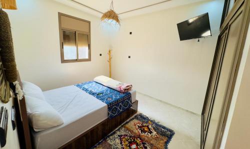 a small bedroom with a bed and a television at Surf Apartment in Tamri Rooftop Local Experience in Tamri