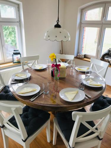 a dining room table with white chairs and a wooden tableablish at Elbferienhaus Lenzerwische - gemeinsames Urlauben an der Elbe mit privaten Badesee - alles inklusive in Lenzerwische