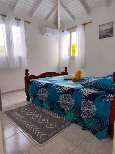 a bedroom with a bed with a blue and white blanket at Haut de villa " JODI " in Sainte-Rose
