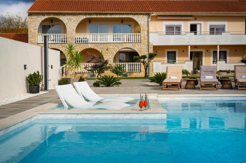 a swimming pool with chairs and a house at My Dalmatia - Apartment Neda with shared pool in Galovac