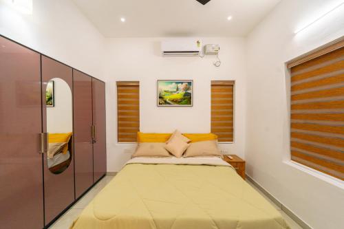 a small bedroom with a bed with yellow pillows at Greenview Royal Stay Near Amrita Hospital Edappally in Cochin