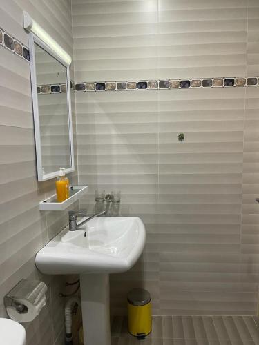 Un baño blanco con lavabo y espejo. en Momo, en Dakar