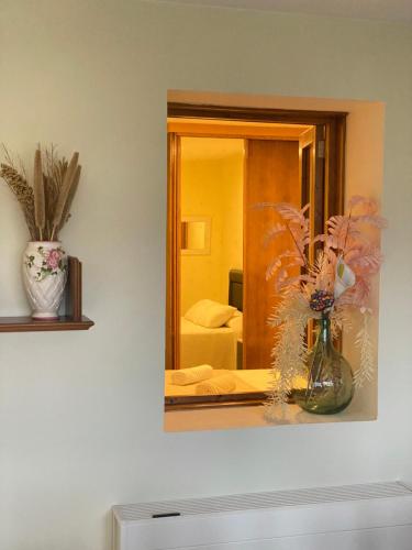 a mirror on a wall with a vase of flowers at CASA do CAMPO Lestrove in Padrón