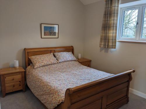 a bedroom with a wooden bed and a window at The Roost at The Gables Farm in Poynton