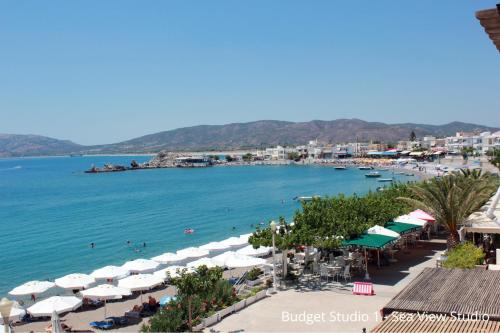 a beach with umbrellas and people on the water at Budget Studios Haraki in Haraki