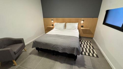 a small bedroom with a bed and a chair at Hotel Manquehue in Esquel