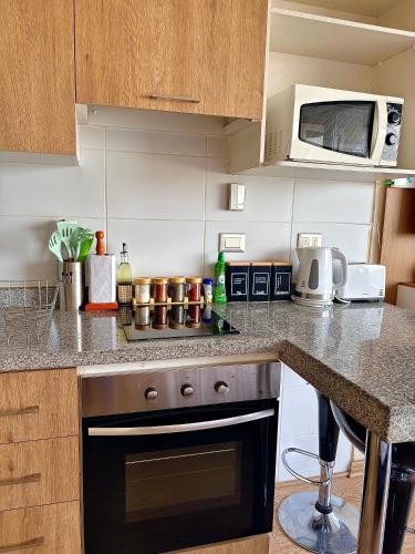 a kitchen with a stove and a microwave at DEPARTAMENTO PREMIUM en Chillán Centro, full equipado, cómodo, con estacionamiento, factura para empresas, wifi de alta velocidad in Chillán