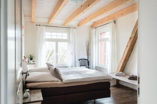 a bedroom with a bed and two windows at Gut-Royum-Grosse-Diele in Brodersby