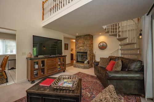a living room with a leather couch and a staircase at Cabin & Canoe by Railey Vacations in McHenry
