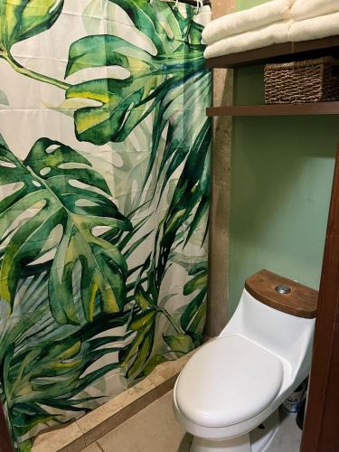 a bathroom with a toilet and a tropical shower curtain at Casa Familiar en La Paz BCS in La Paz