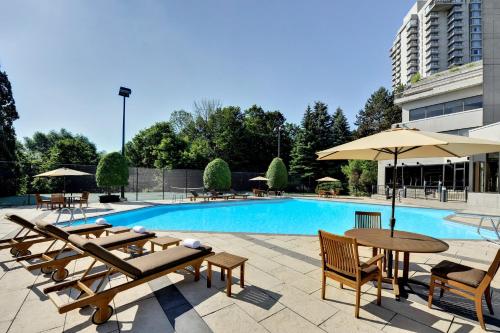a pool with tables and umbrellas next to a building at Crowne Plaza Toronto - North York by IHG in Toronto