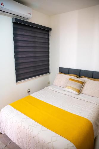 a bedroom with a yellow and white bed and a window at Loft Montecarlo in Hermosillo