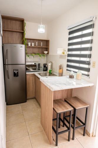 a kitchen with a refrigerator and a table with stools at Loft Montecarlo in Hermosillo
