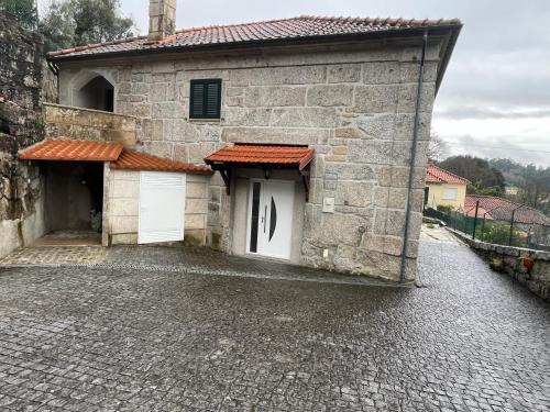 a stone building with two white doors on a cobblestone street at Casa da Ramada - Water SPA Tank with running natural spring water - by Bedzy in Braga