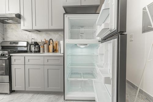 a refrigerator with its door open in a kitchen at Comfy 2B Near LGA & Subway with Washer & Dryer in Corona