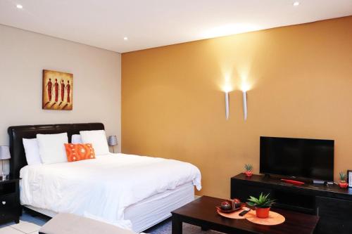 a bedroom with a bed and a flat screen tv at The Orange Corner II in Johannesburg
