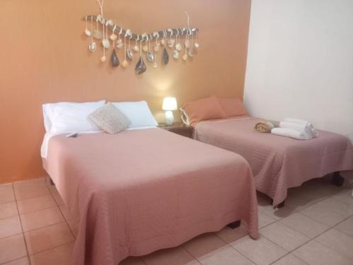 a bedroom with two beds with pink sheets and a chandelier at Casa Amelia in San Blas