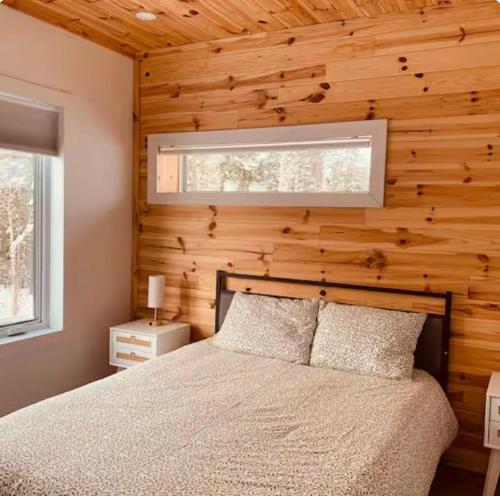 a bedroom with a bed and a wooden wall at NOvO Chalet in Saint-David-de-Falardeau