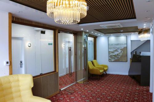 a waiting room with yellow chairs and a chandelier at Park Inn Palace in Dover