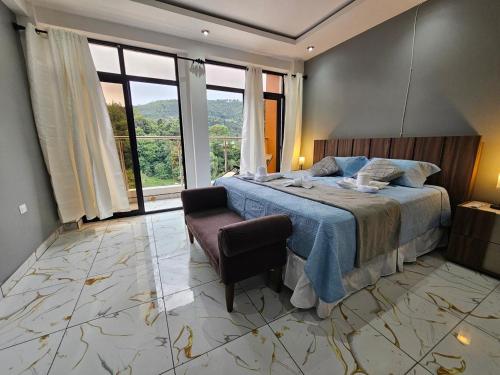 a bedroom with a bed and a chair and windows at Hotel Kiara in Cataltzul