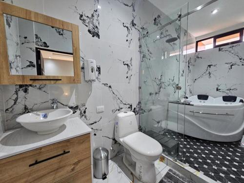 a bathroom with a toilet and a sink and a tub at Hotel Kiara in Cataltzul