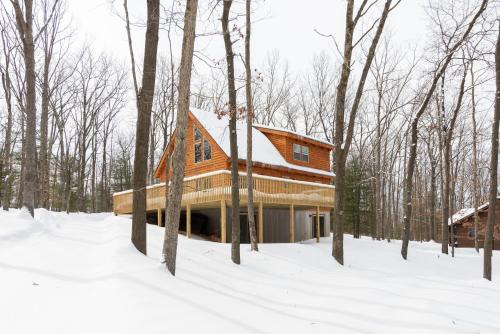 a house in the woods in the snow at Lighthearted Lodge by Railey Vacations in Swanton