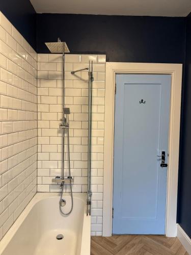 a bathroom with a tub with a shower and a door at Flat in Lundin Links in Lundin Links