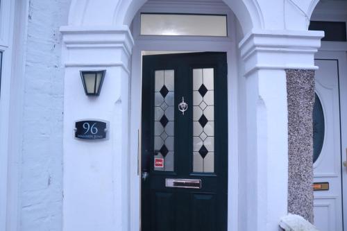 a black door in a white building with a sign on it at 96 Nelgarde Guesthouse in London