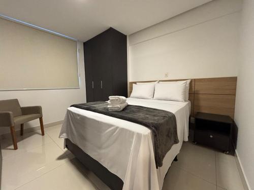 a hotel room with a bed and a chair at Apart St Bueno Ar, Cozinha, Garagem Próx Órion in Goiânia