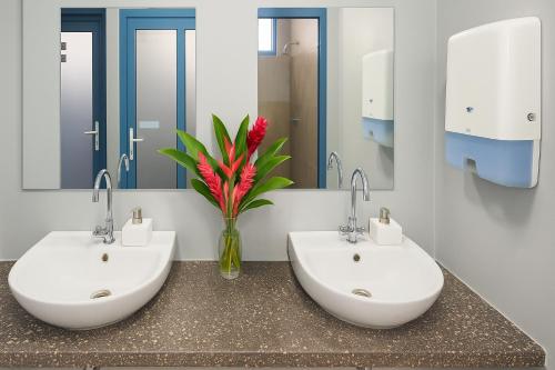 a bathroom with two sinks and a vase with a red flower at The Tree House Port Vila in Port Vila