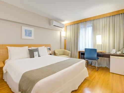 a hotel room with a large bed and a desk at Novotel RJ Santos Dumont in Rio de Janeiro