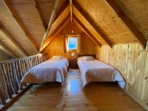 two beds in a room with a roof at Cabañas Antonia in Futaleufú