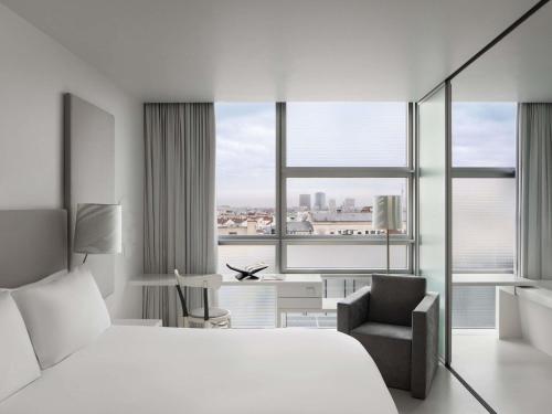 ウィーンにあるSO ウィーンのベッドと椅子のあるホテルの部屋