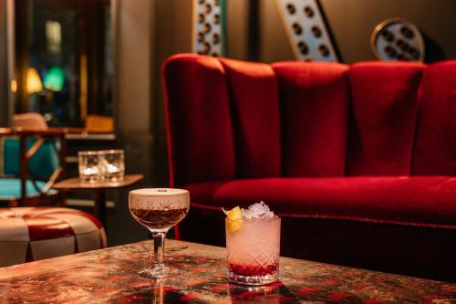 a table with two glasses and a drink on it at Ruby Lucy Hotel London by IHG in London