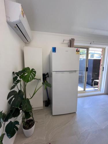 a white refrigerator in a room with a plant at Bright & Quiet 1BR with Courtyard in Williams Landing