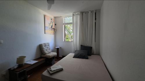 a bedroom with a bed and a chair and a window at Comme à la maison! Le Moule in Le Moule