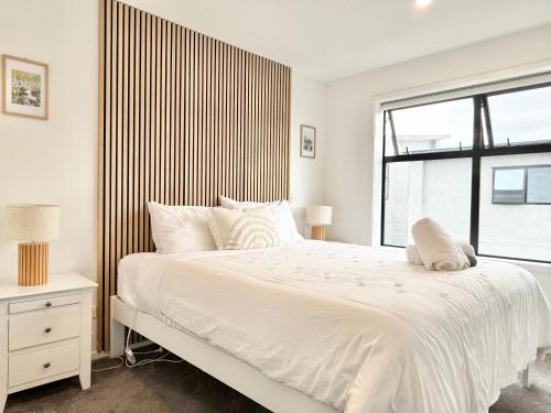 a white bedroom with a large bed and a window at Central 2BRM 2BTH townhouse FREE carpark in Christchurch