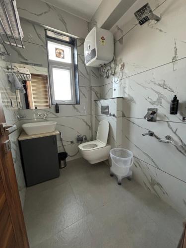a white bathroom with a toilet and a sink at Conifer heights in Shimla