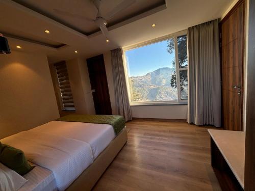 a bedroom with a bed and a large window at Conifer heights in Shimla