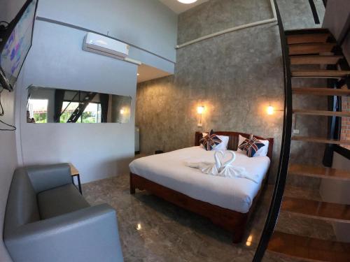 a bedroom with a bed and a staircase and a chair at โรงแรมบีคูลบูทีค in Ban Hua Phrong